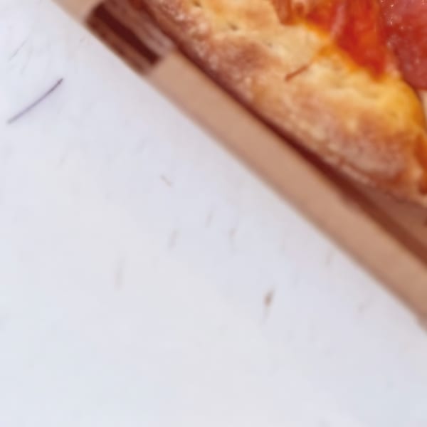 Close-up of a pepperoni pizza slice in a cardboard box from North Beach Pizza.