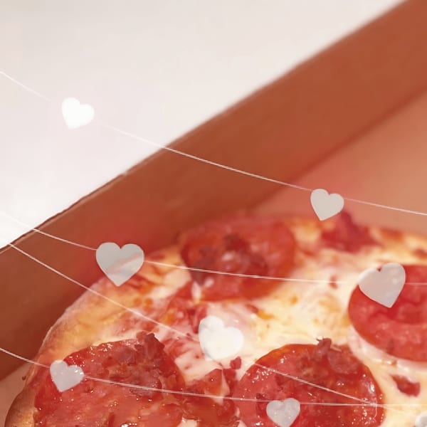 Pepperoni pizza in a delivery box, adorned with delicate white heart-shaped lights.