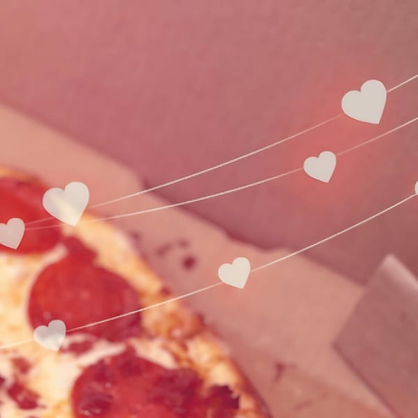 Pepperoni pizza in a box with heart-shaped decorations on strings, creating a romantic mood.