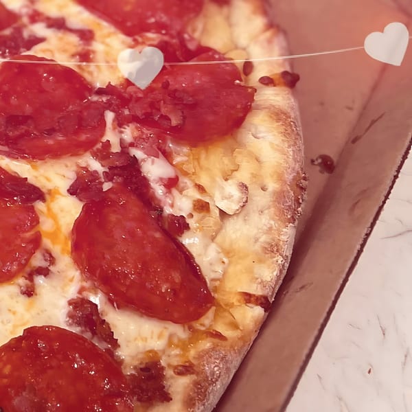 Close-up of a pepperoni pizza from North Beach Pizza, with hearts on a string above.