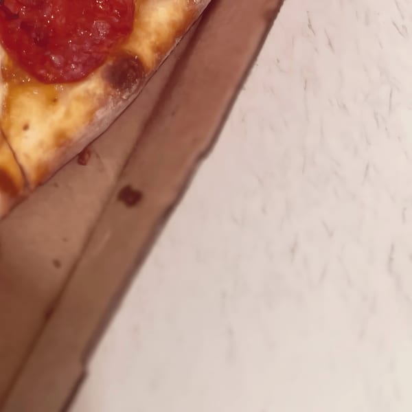 A close-up of a pepperoni pizza slice in a North Beach Pizza box.